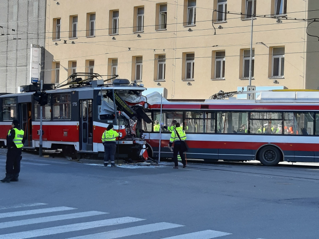 Rote und weiße Straßenbahn war in einen Straßenrandunfall mit wenigen Menschen in der Nähe und einem Gebäude im Hintergrund verwickelt.