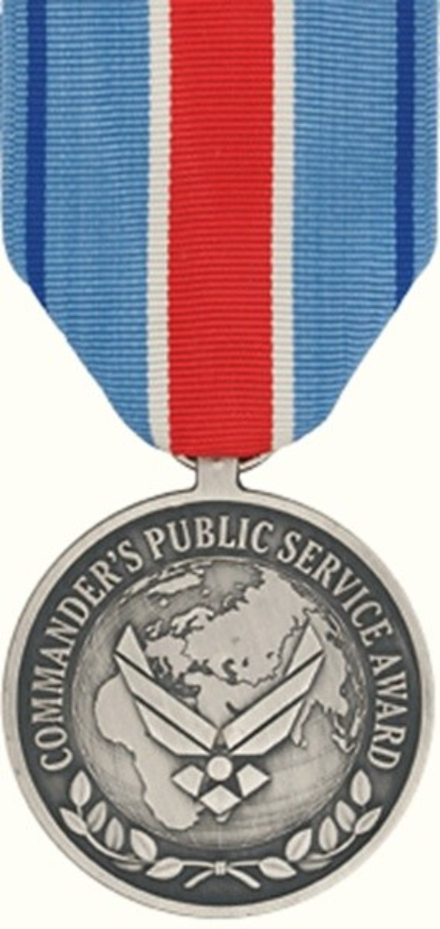 Eine Silbermedaille mit einer rot-weiß-blauen Schleife, auf der der Text 'Commander's Public Service Award' auf einem weißen Hintergrund zu sehen ist.