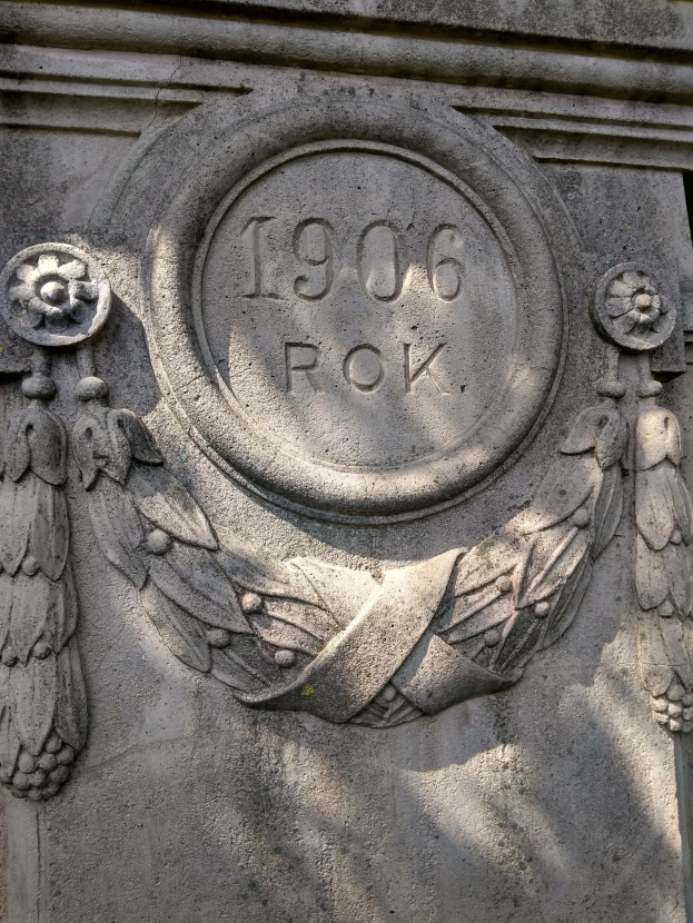 Nahaufnahme eines steinernen Denkmals mit einem Kranz und eingravierter Schrift, wahrscheinlich ein Mahnmal.