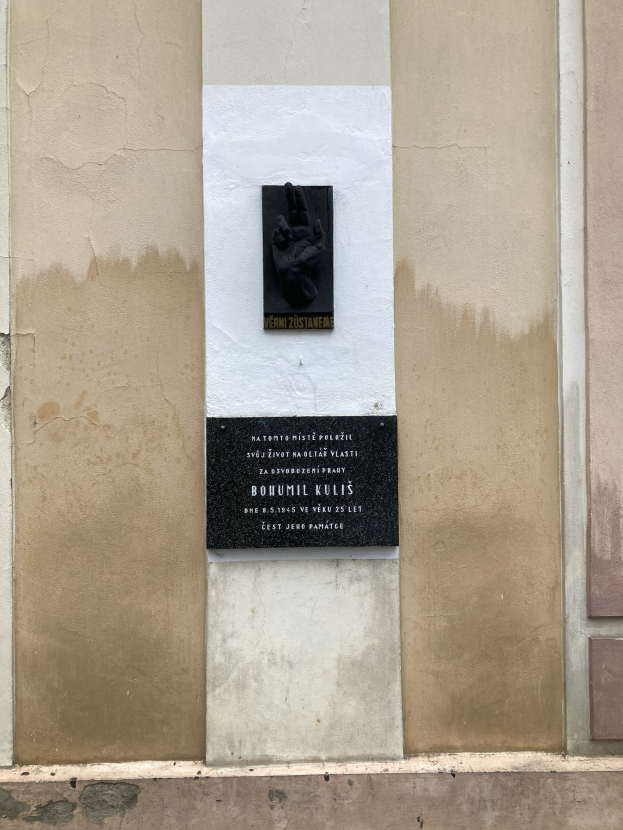 Schwarze Tafel an einem Gebäude mit einer Hand darauf, wahrscheinlich ein Holocaust-Mahnmal mit eingravierten Text.