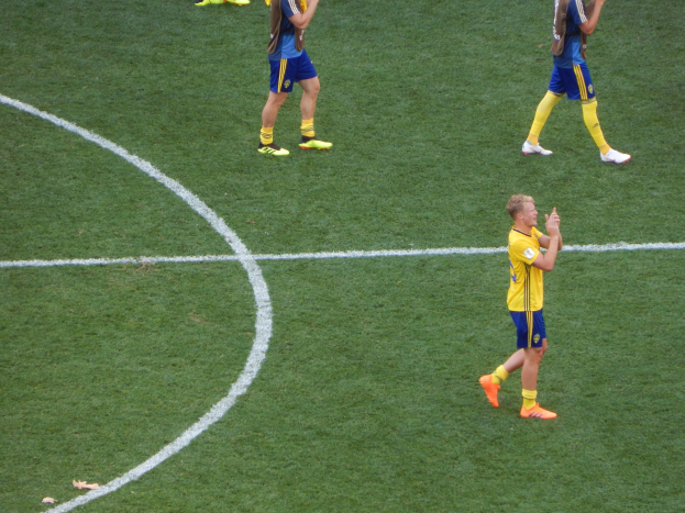 Mannergruppe in Fußballtrikots klatscht auf einem Fußballfeld.