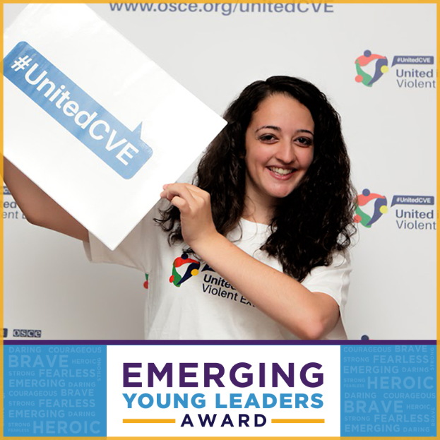 Eine Frau mit strahlendem Lächeln hält ein Schild hoch, auf dem "Emerging Young Leaders Award" steht, ihre Augen strahlen vor Freude und Stolz.