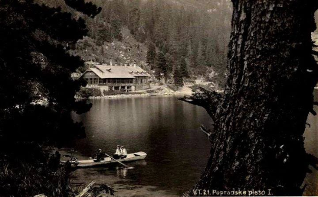Ein Schwarz-Weiß-Foto von zwei Menschen in einem Kanu auf einem See in Popradskie, Polen, aufgenommen in den 1920er Jahren, mit Bäumen und einem Haus im Hintergrund, beide halten Paddel.