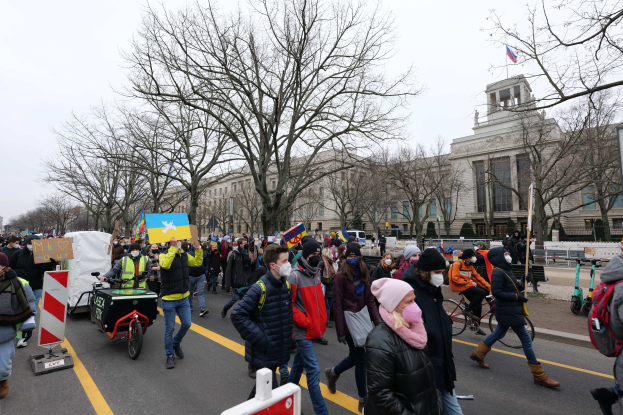 Eine große Gruppe von Menschen marschiert bei einer Demonstration am 21. Januar 2020 in Washington, D.C. über die Straße, mit Schildern und Fahrrädern, mit Bäumen und einem Gebäude im Hintergrund bei klarem blauem Himmel.