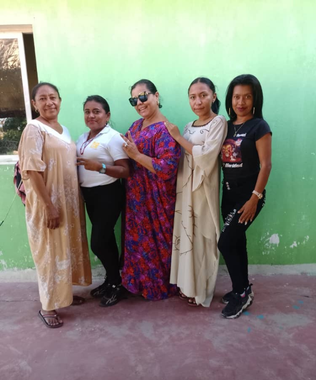 Gruppe von Frauen, die vor einer grünen Wand mit einem Fenster auf der linken Seite stehen und an einem Internationaler Frauentag-Event teilnehmen.