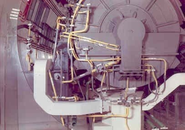 Großes industrielles Accelerator-Gerät mit mehreren angeschlossenen Komponenten und Kabeln in einem Gebäude.