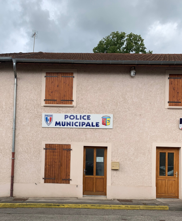 Gebäude der Police municipale mit einem Schild, Fenstern, Türen, einer Namensschild, einer Leitung, einem Baum und einem bewölkten Himmel im Hintergrund.