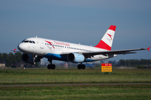 Airbus A320-200 der Austrian Airlines startet vom Frankfurt Airport mit einer Tafel, Gras, Bäumen, Gebäuden und einem klaren blauen Himmel im Hintergrund.