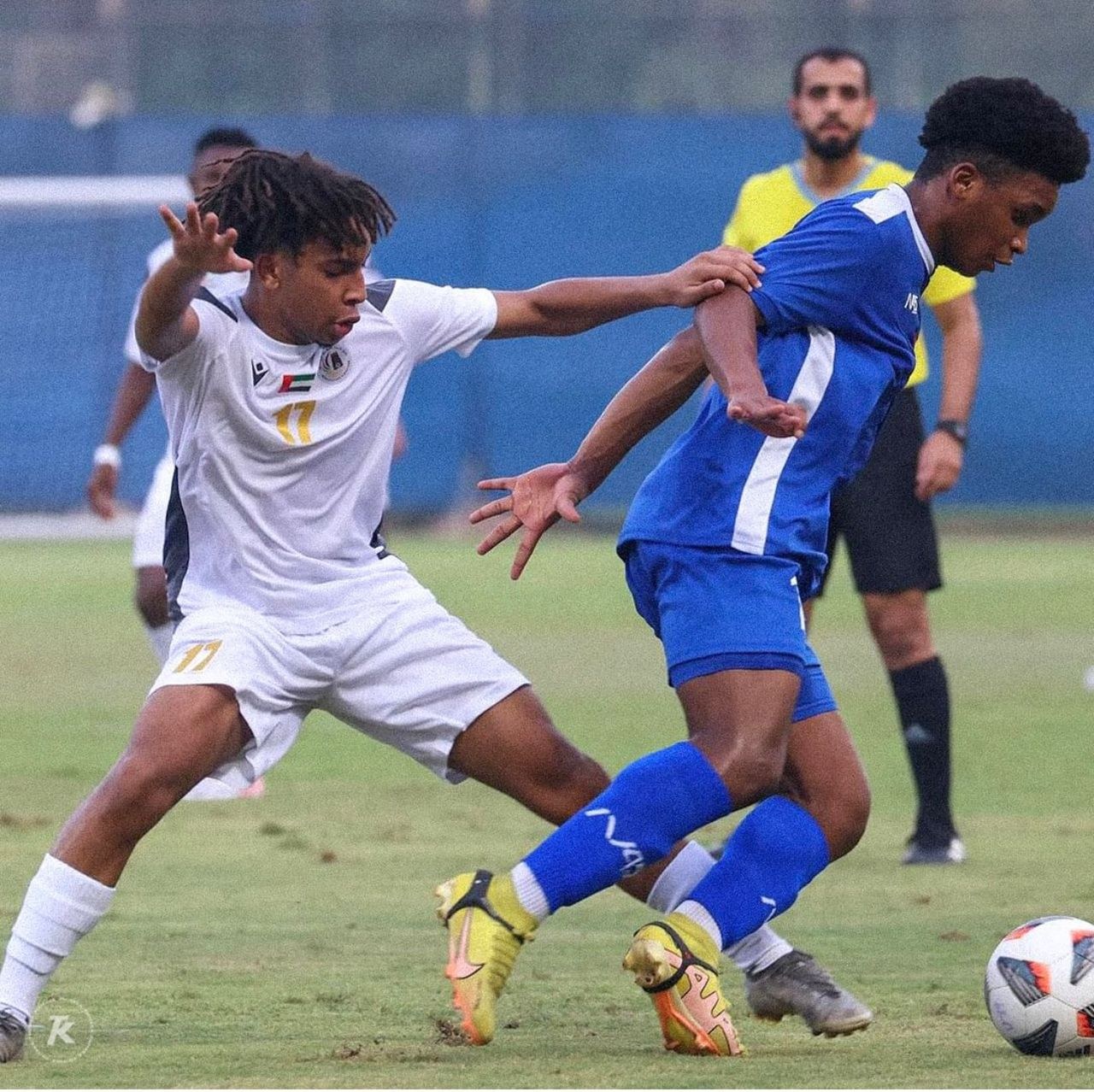 Zwei Männer beim Fußballspielen auf einem Rasenfeld, wobei einer einen Sieg in einem U-17-Spiel zu feiern scheint.