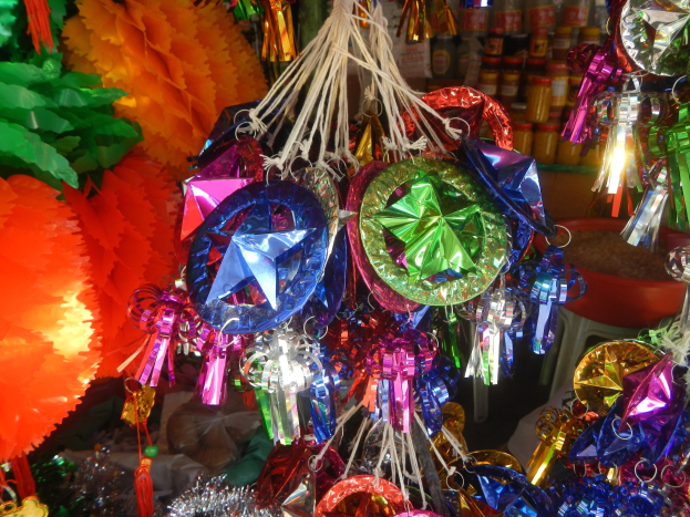 Farbenfrohe Festschmuck, darunter Laternen und Bänder, hängen von der Decke über Regalen mit Flaschen in einer feierlichen Atmosphäre.