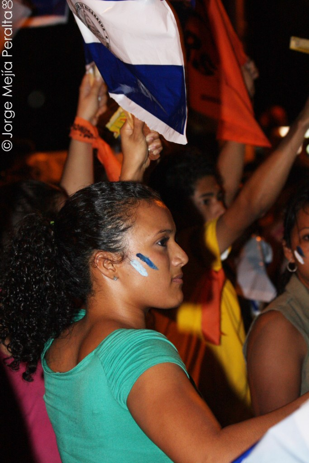 Frauen in grünen T-Shirts bei einer Demonstration, die weiße Abdeckungen halten, mit anderen Mädchen im Hintergrund.