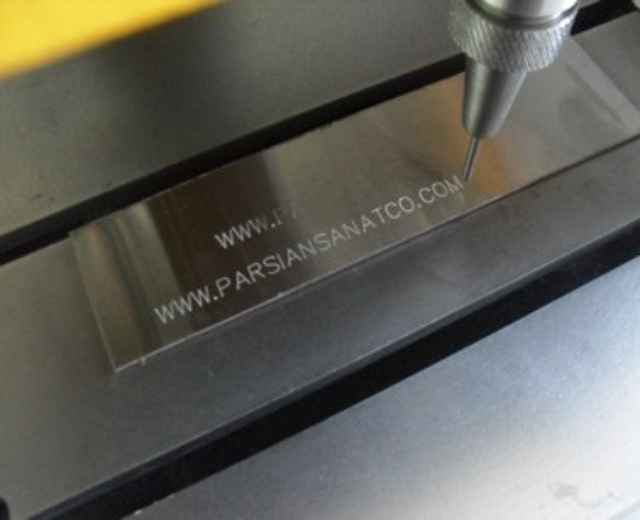 CNC-Fräsmaschine schneidet ein Metallteil mit Text darauf.