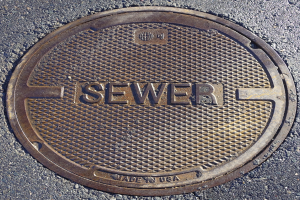 Metall-Schachtdruckgussdeckel auf der Straße mit der eingravierten Aufschrift "Kanal"