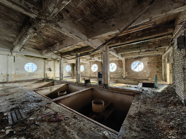 Verlassener Gebäuderaum im Chernobyl-Ausschlussgebiet mit verstreuten Trümmern, freiliegenden Wänden, Decke und konstruktiven Elementen.