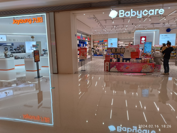 Innenansicht eines Babyladens im Mall of Asia mit Menschen, Spielzeugen, Regalen, Schildern, einem Anzeigebildschirm und Deckenleuchten.