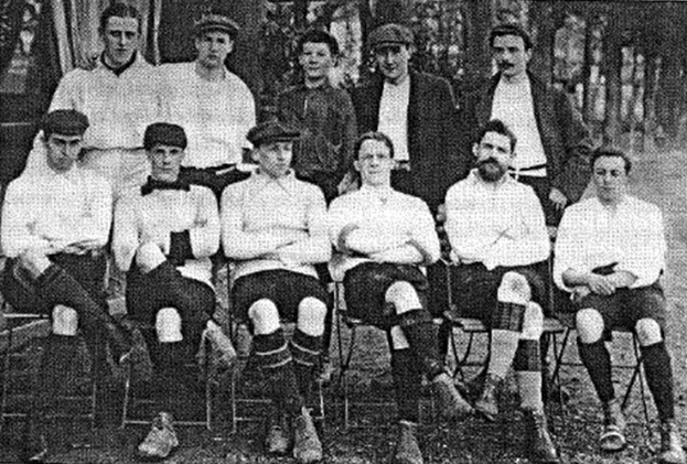 Schwarze und weiße Mannschaftsfoto von West Bromwich Albion Football Club aus dem Jahr 1918, mit sitzenden und stehenden Spielern vor Bäumen.