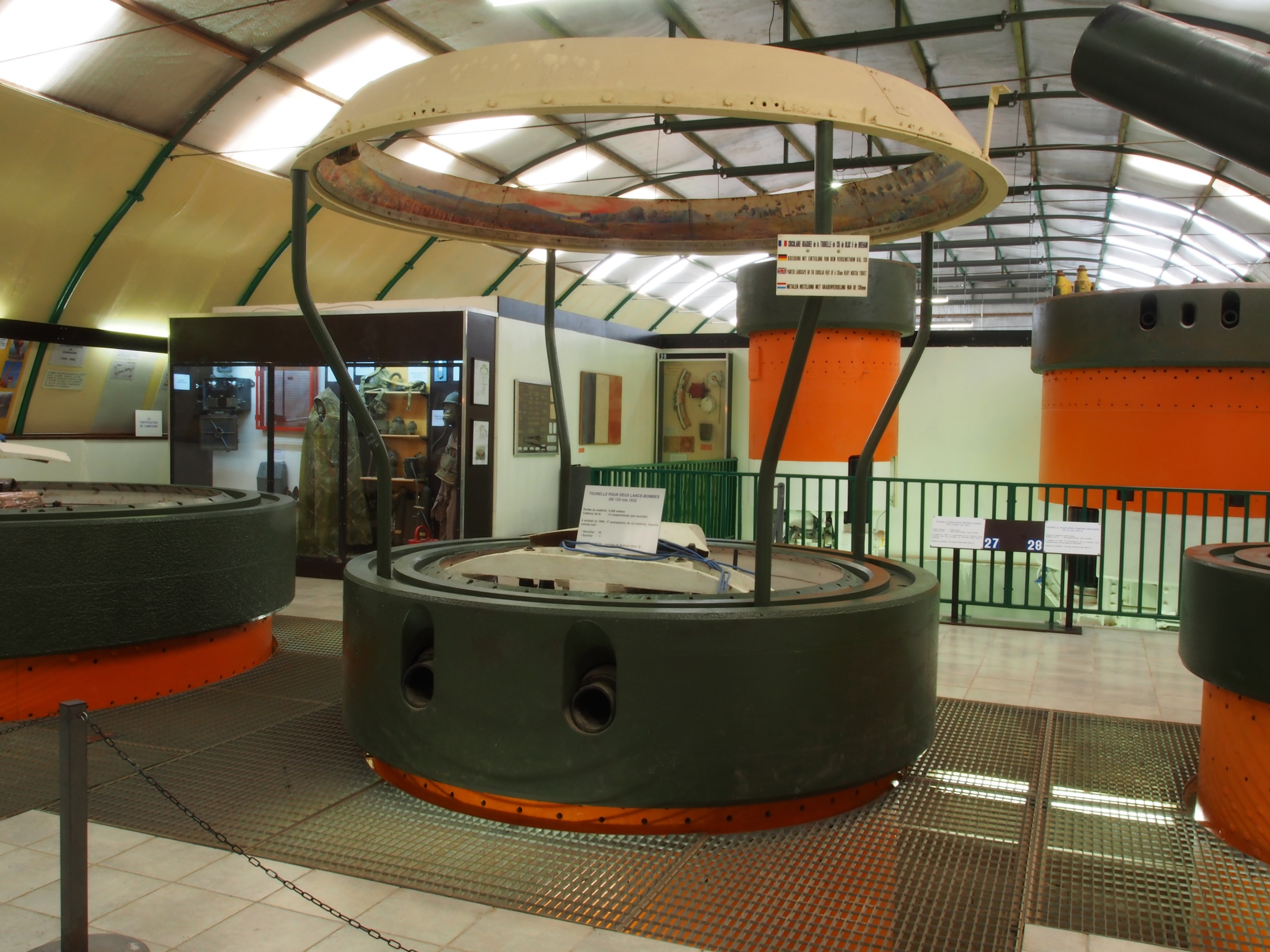 Ein großer Industrieraum mit verschiedenen Maschinen, darunter ein Rotor, eine Kette, Pole, Texttafeln, ein Zaun, Wand, Decke und Beleuchtung.