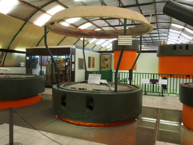 Ein großer Industrieraum mit verschiedenen Maschinen, darunter ein Rotor, eine Kette, Pole, Texttafeln, ein Zaun, Wand, Decke und Beleuchtung.